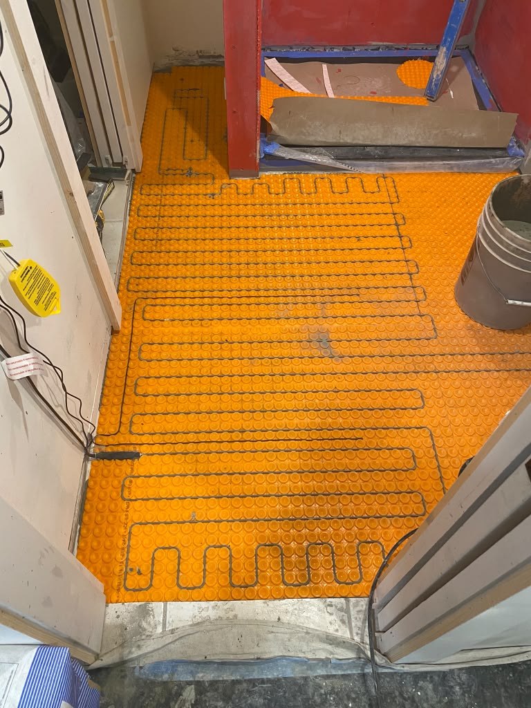 Heated floor mat laid before tile
